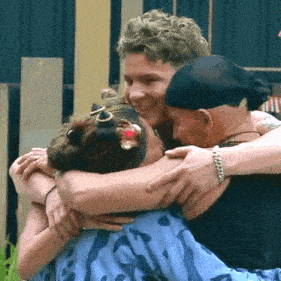 a woman with a flower in her hair is hugging two other people