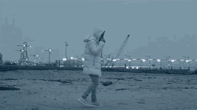 a person in a white jacket is walking on a sandy beach