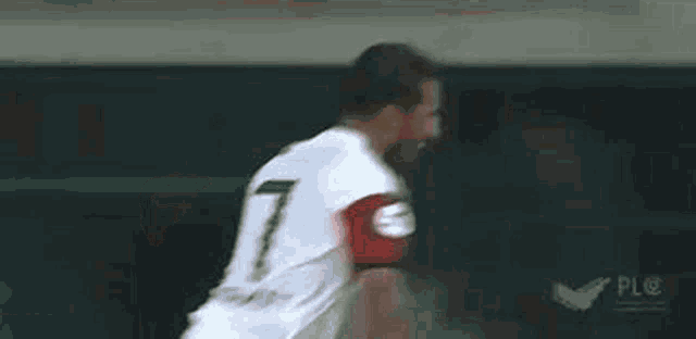 a soccer player wearing a white jersey with a red armband with the number 9 on it .