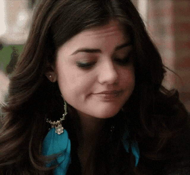 a woman wearing a pair of blue feather earrings