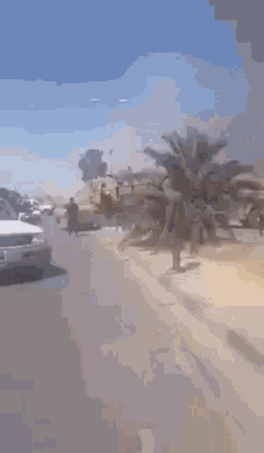 a group of people are walking down a street in front of a military vehicle .