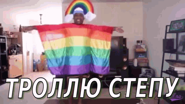 a man is wearing a rainbow cape and a rainbow hat while standing in a living room .