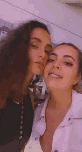 two women are posing for a picture and one is kissing the other