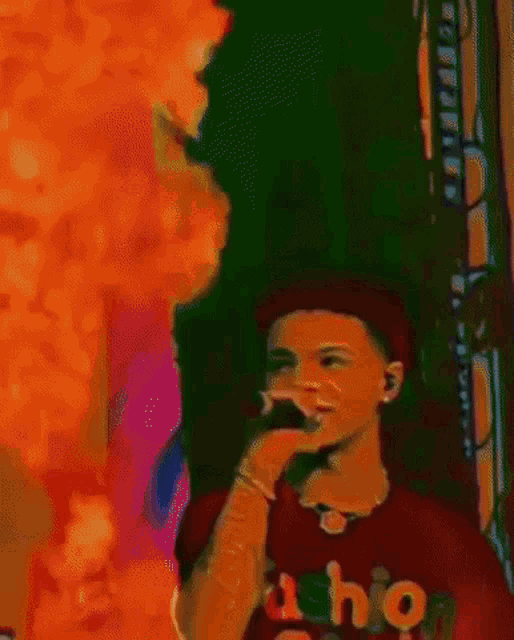 a young man is singing into a microphone while wearing a t-shirt that says fashion
