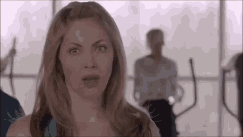 a woman is making a funny face while standing in a gym with other people .