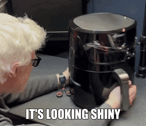 a man looking at an air fryer with the words it 's looking shiny above him