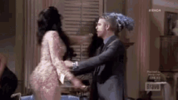 a man in a suit and a woman in a dress are hugging each other in a room .