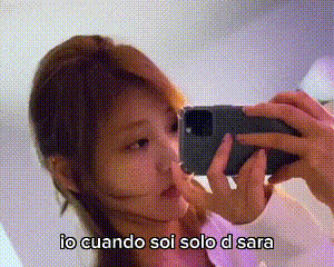 a woman is taking a selfie with a cell phone in front of a mirror .