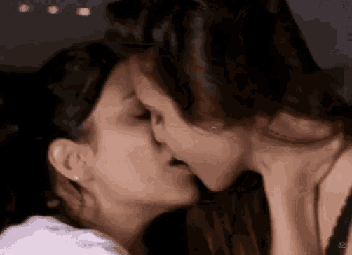 a couple of women are kissing each other on the cheek .