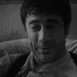a man in a suit and tie is laying on a bed and smiling .