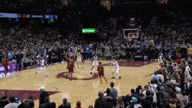 a basketball game is being played in front of a crowd with a green washington sign