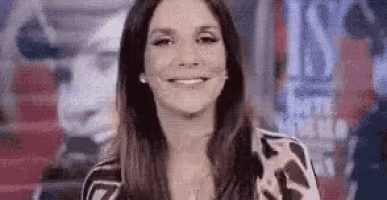 a woman with long hair is smiling and looking at the camera in a blurry photo .