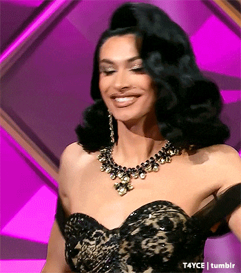 a woman wearing a black dress and a gold necklace is smiling .