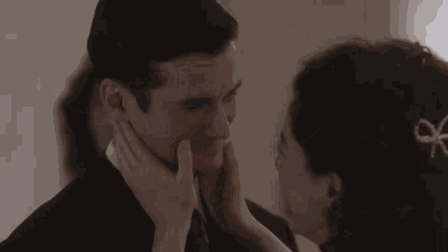 a woman touches a man 's face with her hand