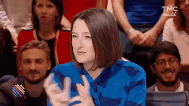 a woman in a blue shirt is sitting in front of a crowd .