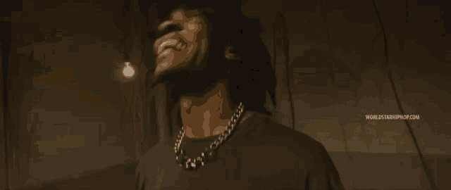 a man with dreadlocks is wearing a black shirt and a chain around his neck