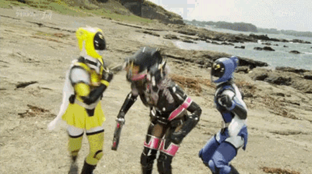three power rangers are standing on a beach near the water