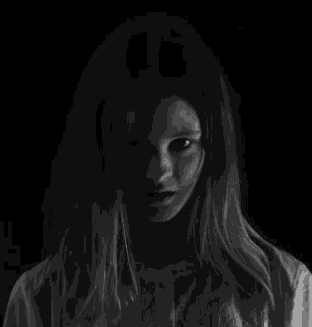 a black and white photo of a girl with long hair looking at the camera