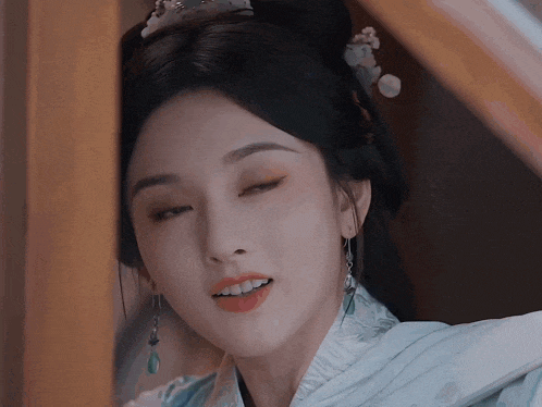 a close up of a woman 's face with her eyes closed and a flower in her hair