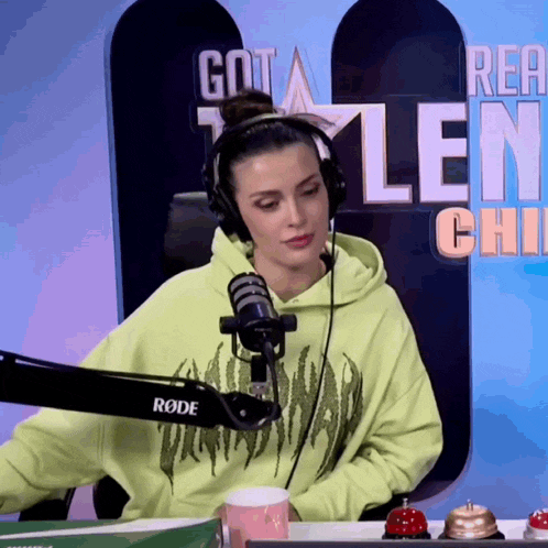 a woman wearing headphones and a neon green hoodie is sitting in front of a rode microphone