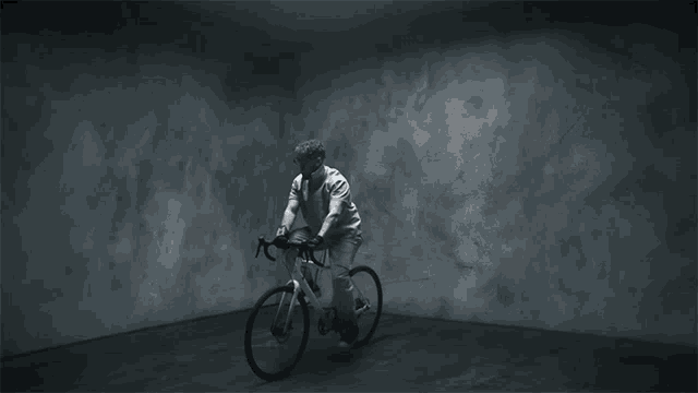 a man rides a bike in a dark room
