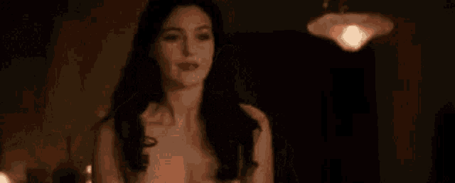a woman with long black hair is standing in a dark room .