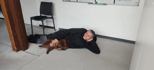a man laying on the floor with a brown dog