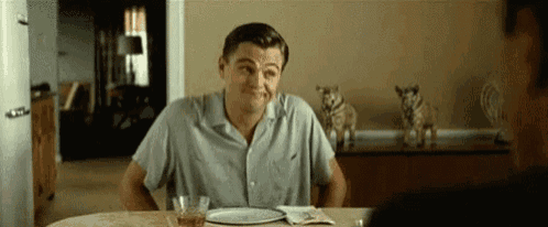 a man is sitting at a table with a plate of food and a glass of wine .