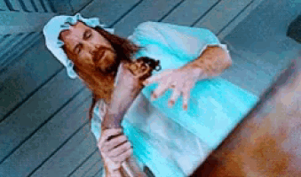 a man with long hair is holding a doll in his hands .