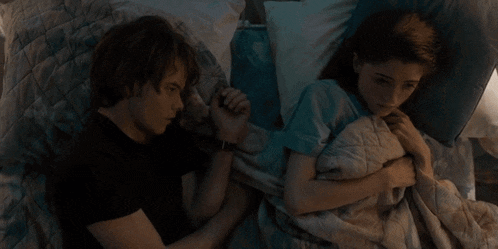 a man and a woman are sleeping in a bed and holding hands