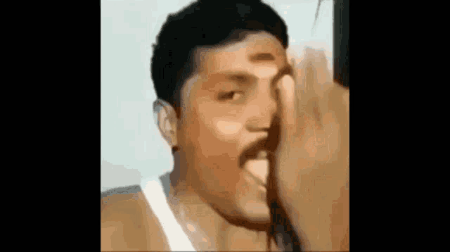 a man with a mustache is covering his mouth with his hand