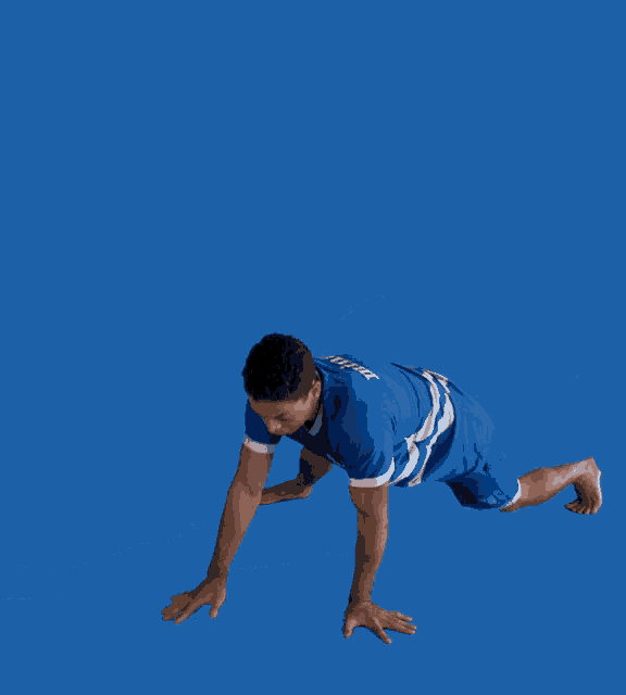 a man in a blue shirt and shorts is doing a trick with his leg