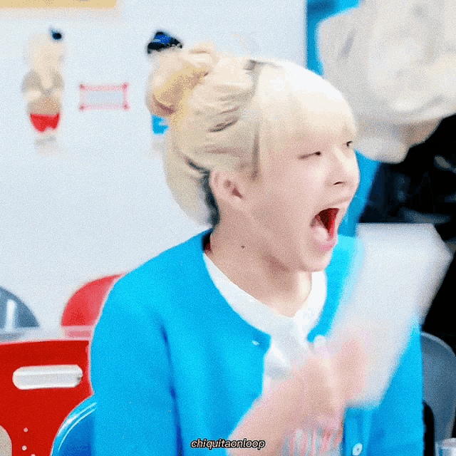 a girl with blonde hair is wearing a blue sweater and a white shirt