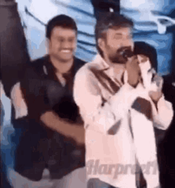 a man with a beard is singing into a microphone in front of a crowd of people .