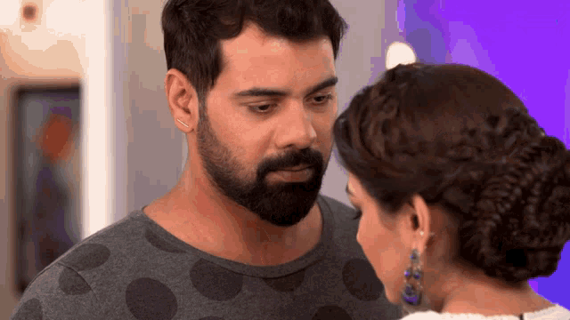 a man with a beard looks at a woman with a braided hairdo