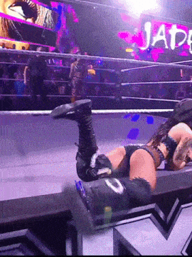 a woman is laying on the ground in a wrestling ring with a sign that says jat
