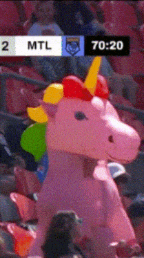 a pink inflatable unicorn stands in the stands during a game between the mtl and the toronto raptors