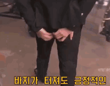a man in a suit is standing with his hands on his hips in front of a projector screen with korean writing on it