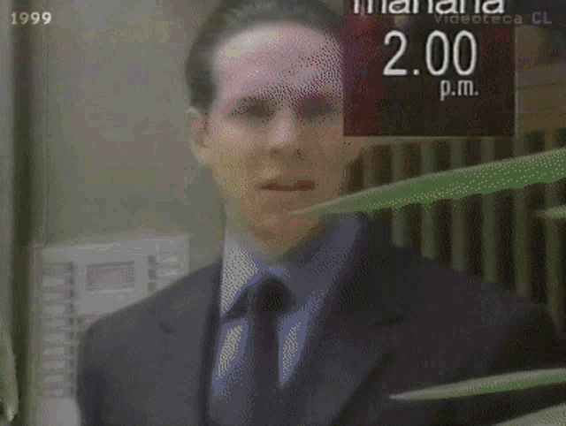 a man in a suit and tie is standing in front of a sign that says manana 2.00 p.m.
