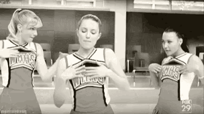 a group of cheerleaders are standing next to each other in a room .
