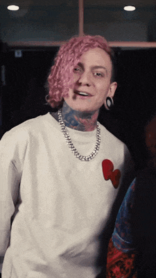 a man with pink hair is wearing a white shirt and a necklace