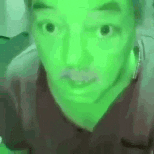 a close up of a person 's face with a green light behind it .