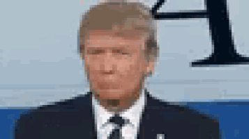 donald trump is wearing a suit and tie and making a funny face while sitting on a couch .