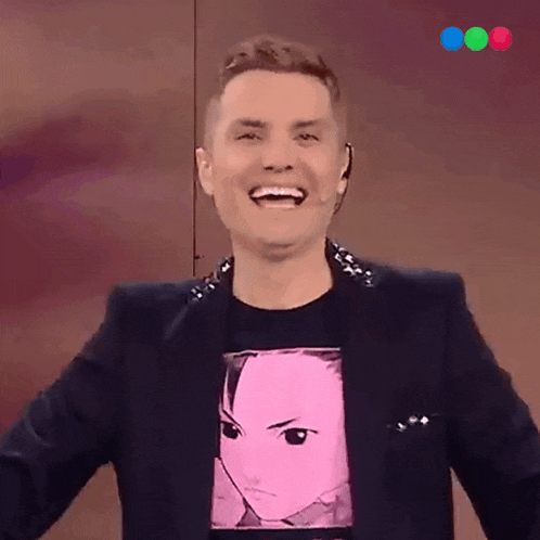 a man wearing a black jacket and a pink shirt with a face on it is smiling