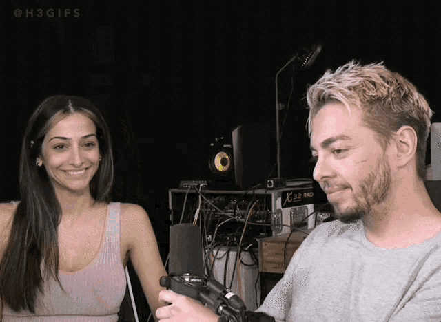 a man and a woman are smiling at each other in front of a microphone that says h3gifs on it