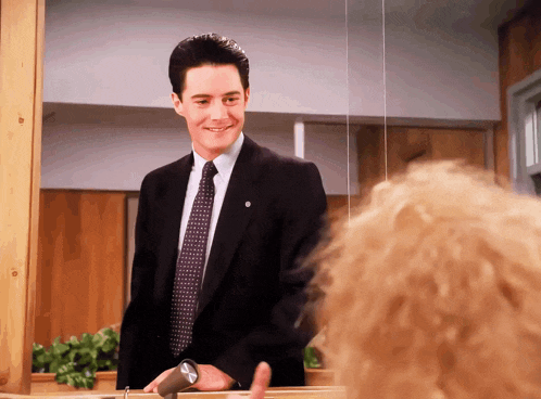a man in a suit and tie stands in front of a woman