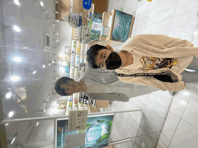 a man wearing a mask stands next to another man in front of a sign that says ' nature republic '