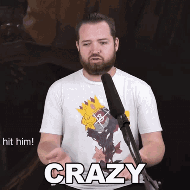 a man with a beard is talking into a microphone with the word crazy written on his shirt