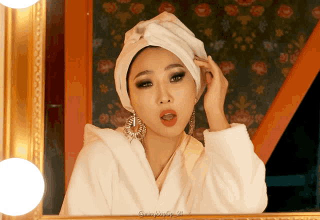 a woman with a white towel wrapped around her head looks at herself in a mirror