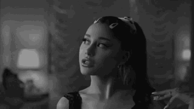 a black and white photo of ariana grande smoking a cigarette in a living room .
